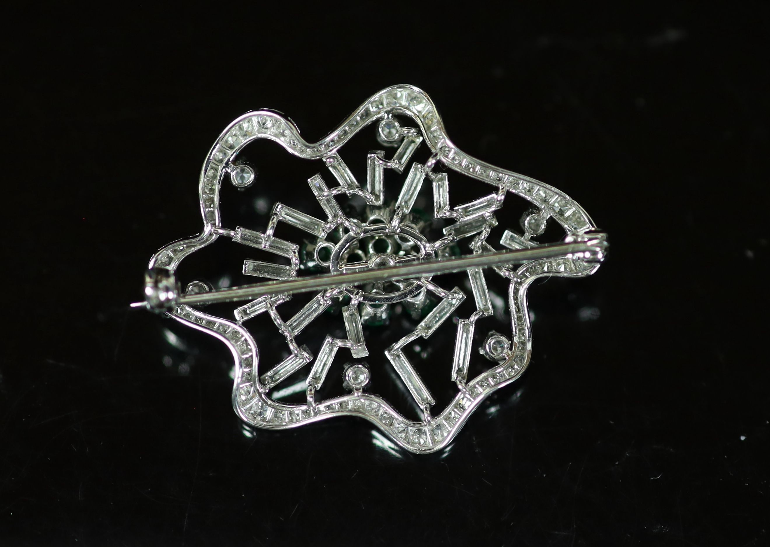 A white gold, emerald and diamond set open work modernist brooch
